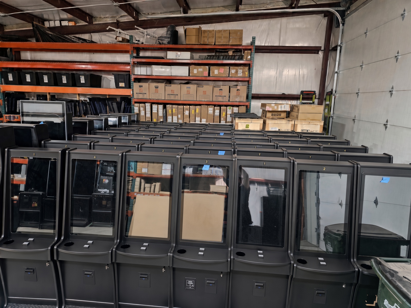 Rows of finished NCG game cabinets and parts inventory in our warehouse facility